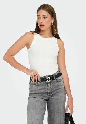 Hvid ærmeløs top med rund hals, prydet med små dekorative nitter; parret med højtaljede grå jeans og et sort bælte.