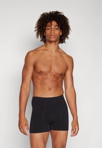 Svarta boxershorts tillverkade av mjukt tyg, med en figurnära passform och en slät midjeresår. Stilen är enkel och funktionell.