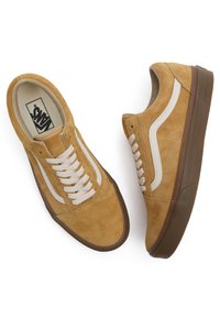Suede sneakers i brunt med hvite lærstripe på siden. Har snøring, rund tå og brun gummisåle.