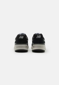 Melni un pelēki skriešanas apavi ar acs audumu, zamšādas akcentiem, mīkstu apkaklīti un polsterētu zolīti. Uz heel ir New Balance logo.