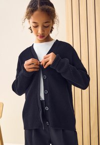 Zwarte gebreide cardigan met V-hals, lange mouwen en vijf knoopsluitingen, met ribbelstructuur en een ontspannen pasvorm.