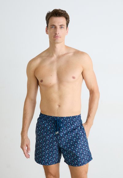 Navy swim shorts with a floral pattern in teal and green. Features an elastic waistband with a drawstring and side pockets.