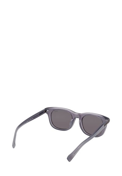 Harmaat aurinkolasit, läpikuultavalla rungolla ja tummilla linsseillä. Suorat sankarit, joissa on teksturoidut korostukset saranan lähellä.