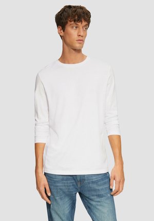 Weißes langärmliges T-Shirt aus Baumwolle mit Rundhalsausschnitt und taillierten Ärmeln, getragen mit blauen Jeans. Schlichtes, klassisches Design.