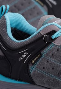Graue Wanderschuhe mit blauen Akzenten, wasserdichtem Gore-Tex-Material, strukturiertem Stoff und einem Variofix-Anpassungsmechanismus.