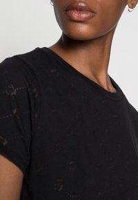 Sort t-shirt med ros mønster tekstur, korte ærmer og en rund halsudskæring, lavet af blødt materiale. Accentueret af let gennemsigtighed.