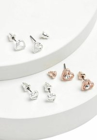 Set de patru cercei tip șurub: două modele de inimă argintie cu margini texturate, două inimi din aur roz cu pietre transparente, toate pe un fundal deschis.