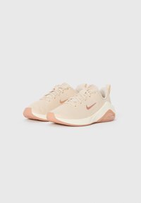 Beige sportieve schoenen met een bovenwerk van mesh, lichtroze accenten, vetersluiting en een gevoerde zool. Bevat logo aan de zijkant en op de hiel.