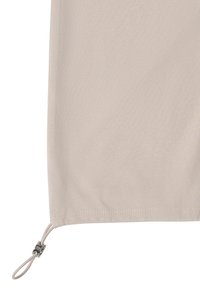 Panneau en tissu beige avec une boucle de cordon ajustable nouée et un fermoir en métal dans le coin inférieur sur un fond blanc.