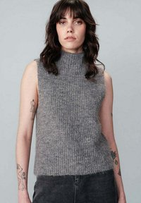 Grijze mouwloze sweater met geribbelde textuur, hoge hals en een relaxte pasvorm. De stof lijkt zacht, met een subtiele glans en nette randen.