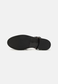 Svart sandaler med en slät läderöverdel, justerbar rem och en platt gummisula med strukturerad dekoration.