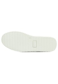 Semelle en caoutchouc blanche avec un motif texturé et strié ; étiquette de marque rectangulaire et petit logo circulaire embossé sur la surface.