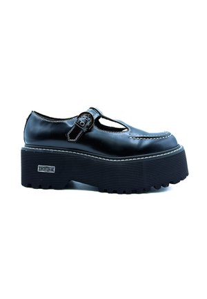 Scarpa con piattaforma in pelle nera, punta arrotondata, design a T e chiusura con fibbia. Suola in gomma testurizzata con scanalature profonde. Dettaglio di cucitura bianca.