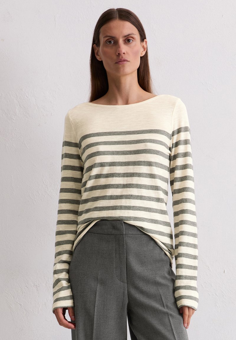 Langarm gestreiftes Oberteil in Creme und Grau, mit einem Boot-Ausschnitt und lässigem Schnitt. Kombiniert mit maßgeschneiderten grauen Hosen.
