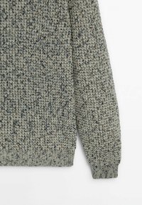 Pull en tricot de couleur gris doux avec des éclats sombres et clairs. Motif texturé, poignets et ourlet côtelés. Matière douce avec une coupe décontractée.