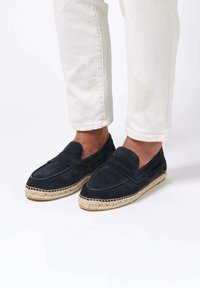 Espadrilles in suede blu navy con design cucito, punta a mandorla e suola in juta. Abbinate a pantaloni bianchi con risvolto.
