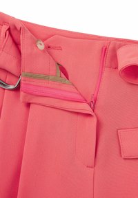 Roze stoffen broek met een rits, knoopsluiting en riemlussen. Het interieur heeft een beige zak en voeringdetails.