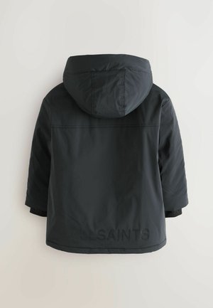 Giacca a vento nera con cappuccio, caratterizzata da una texture opaca e un logo impresso sulla schiena. Design semplice e minimalista con una vestibilità dritta.