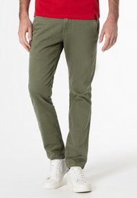 Olivgrüne Baumwollchinos mit geradem Schnitt, ausgestattet mit zwei Seitentaschen und einer glatten Textur, kombiniert mit weißen High-Top Sneakers.