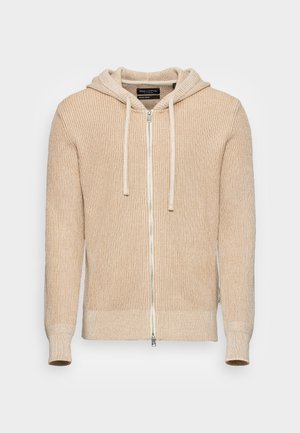 Beige ribbed hoodie with a full zipper, drawstring hood, and textured knit pattern. Fitted cuffs and waistband provide a snug fit.