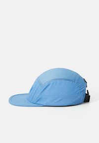 Light blue cap made from breathable fabric, featuring a curved visor, textured panels, and adjustable strap for fit.