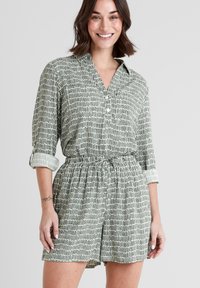 Green and white patterned short romper with a collared neckline, rolled sleeves, drawstring waist, and side pockets. Smooth fabric texture.