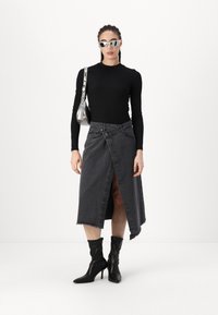 Black long-sleeve top, gray denim wrap skirt with frayed hem, and knee-high black heeled boots. Silver handbag and sunglasses complete the look.