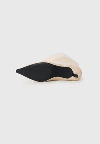 Beige high-heeled boot laying on its side showing the pointed black sole and slender heel against a white background.