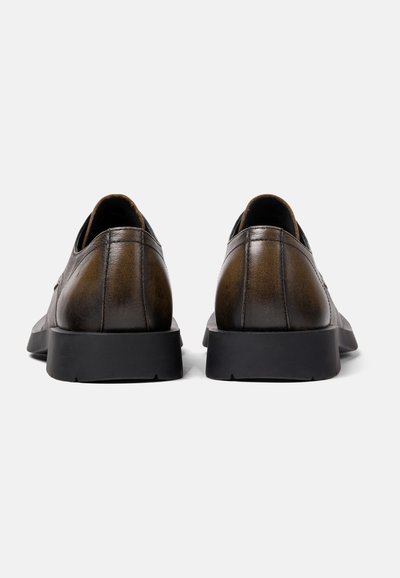 Bruine leren schoenen met een gladde afwerking, ronde vorm en zwarte rubberen zolen. Heeft subtiele stikdetails en een strakke uitstraling.