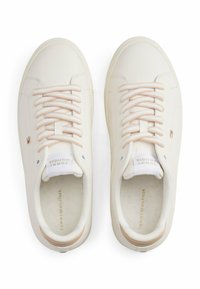 Białe skórzane trampki z beżowymi akcentami, z okrągłymi sznurowadłami i gładką fakturą. Wytłoczony detal z logo na języku i boku.