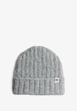 Grijze gebreide beanie met een geribbelde textuur. Heeft een zachte, fuzzy stof en een klein wit merklabel. Rond bovenkant met een omgeslagen rand.