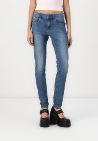 Jeans de mezclilla azul delgada con una cintura de altura media, que cuentan con bolsillos frontales, cierre de botón y un diseño minimalista.