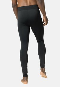 Schwarze Leggings bestehen aus einem glatten, elastischen Stoff mit einem strukturierten Bund und dezenten Mustern an den Seiten. Sie haben ein körpernahes Design.