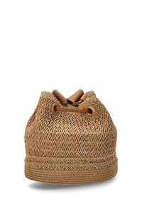 Bolsa redonda de paja trenzada en color marrón claro con un acabado texturizado. Presenta un cierre de cordón de cuero marrón y un sutil detalle trenzado en la base.
