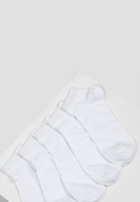 Fünf Paare kurzer weißer Socken aus Baumwolle mit gerippten Bündchen und glatter Textur, ordentlich auf einem hellen Hintergrund angeordnet.