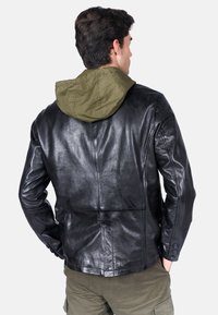 Giacca di pelle nera con cappuccio in tessuto verde, texture liscia, vestibilità su misura, dettagli con polsini abbottonati e design minimalista sul retro.