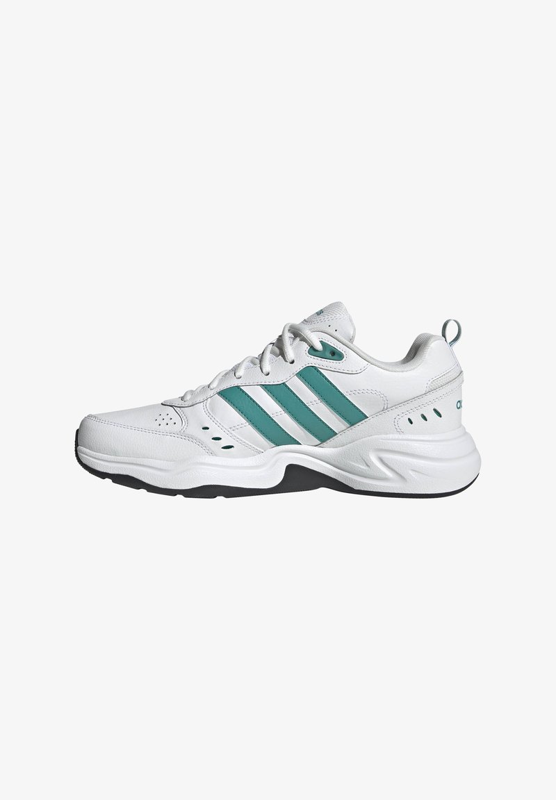 Chaussure de sport blanche avec trois rayures vertes, une surface texturée, un col rembourré et une semelle en caoutchouc. Marque emblématique sur le talon.