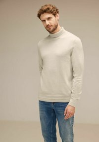 Ljusgrå polotröja i mjukt material, med långa ärmar och ribbade manschetter. Matchas med blå jeans.