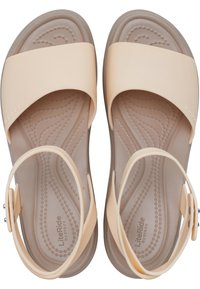 Sandales beige clair avec un design à brides croisées, en matériau en caoutchouc doux, avec une semelle intérieure texturée et une bride de cheville ajustable.