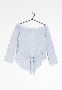 Blouse rayée bleu clair à épaules dénudées avec de longues manches évasées, un closure noué à l'avant et un tissu légèrement texturé.