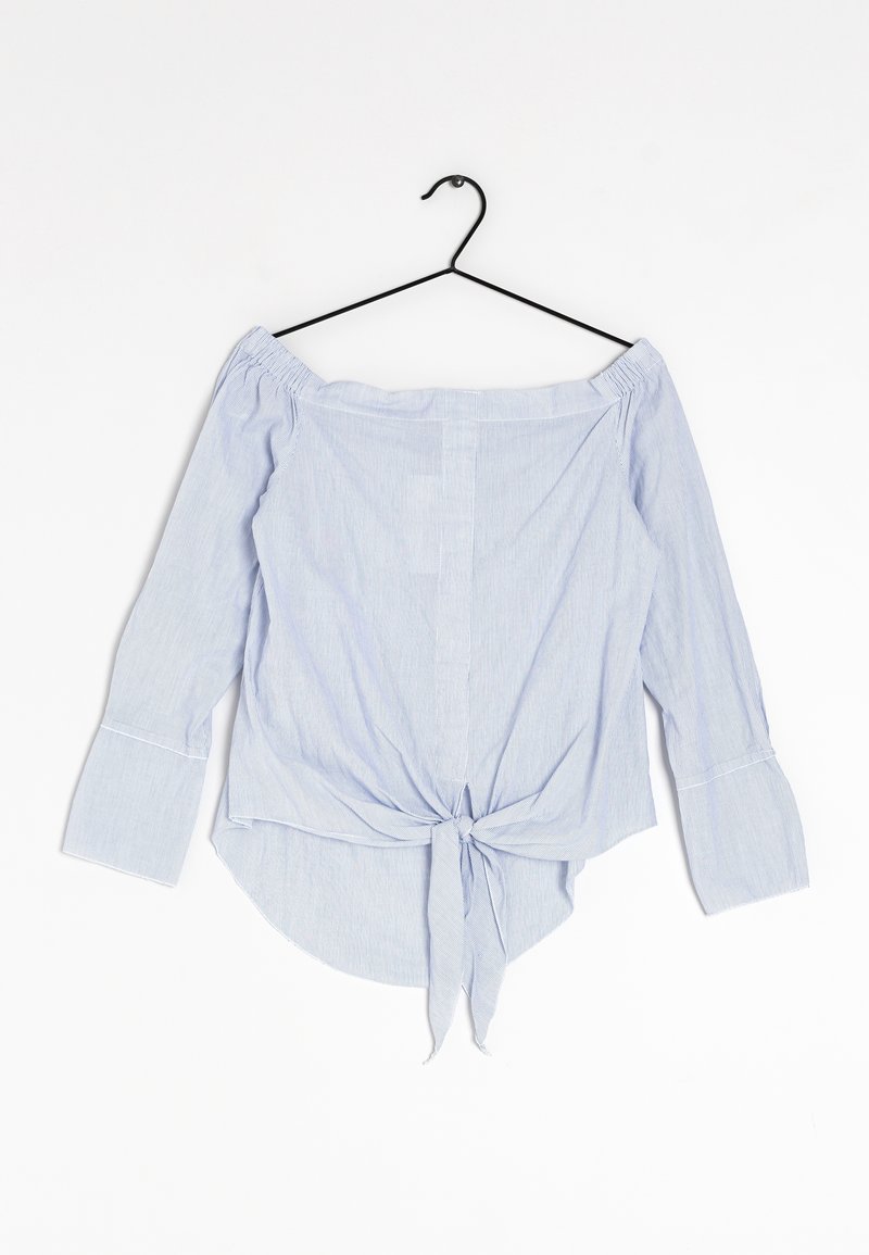 Blouse rayée bleu clair à épaules dénudées avec de longues manches évasées, un closure noué à l'avant et un tissu légèrement texturé.