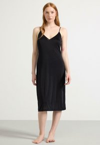 Schwarzes Satin-Nachthemd mit dünnen Trägern, V-Ausschnitt und geradem Schnitt bis zur Wadenmitte. Glatte Textur und minimalistisches Design.