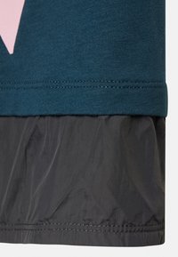 Tecido azul-petróleo com um design rosa na parte superior, transicionando para um material texturizado preto na parte inferior. A bainha apresenta uma borda costurada.