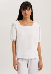 Blusa bianca in cotone con scollatura quadrata, maniche a sbuffo corte e vestibilità rilassata. Tessuto liscio con dettagli minimi.