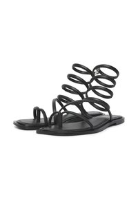 Schwarze flache Sandalen mit einzigartigem Spiralriemen-Design, featuring dünnen Riemen und einer glatten, matten Oberfläche. Minimalistischer Stil.