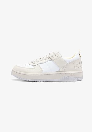 Niskoprofilowe beżowo-białe sneakersy z sznurowanym zapięciem, gumową podeszwą oraz tłoczonym logo "HUGO" na pięcie i boku podeszwy.