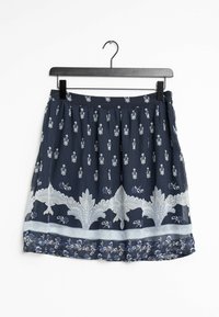 Jupe marine avec des motifs floraux, des accents en dentelle délicate et une taille froncée. Le tissu semble léger et fluide. Accrochée à un cintre noir.