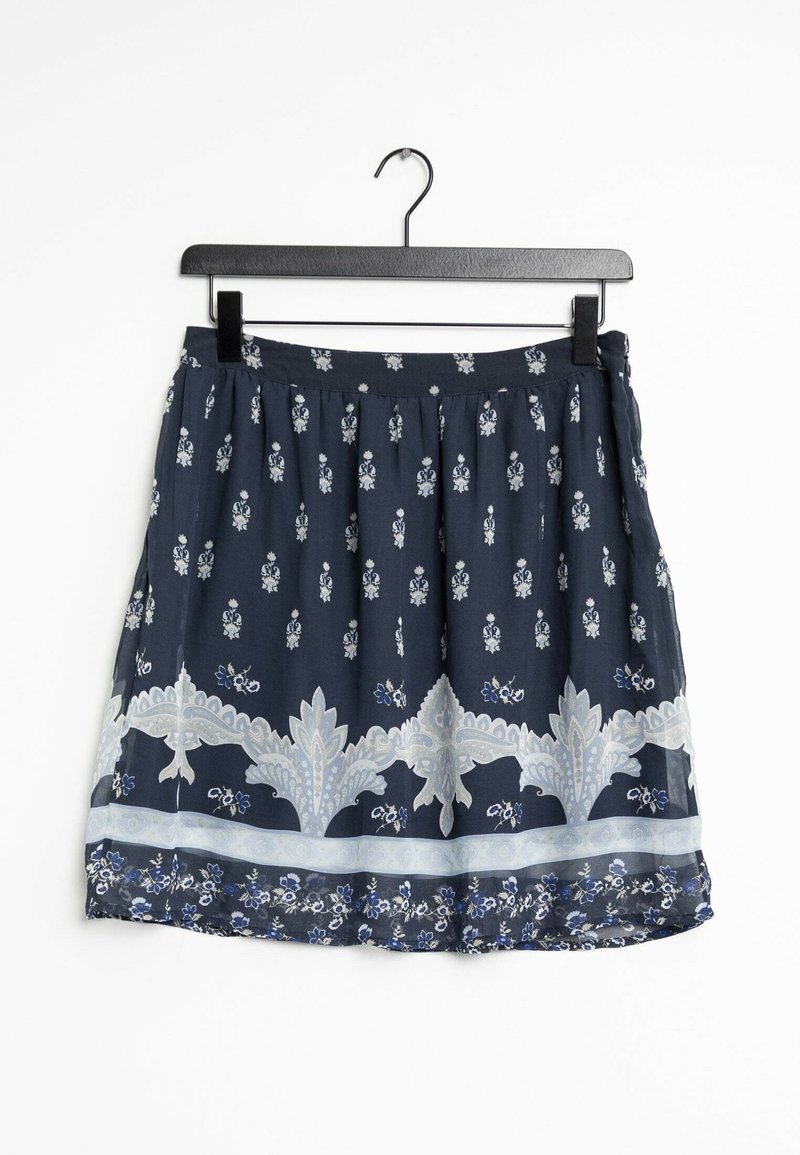 Jupe marine avec des motifs floraux, des accents en dentelle délicate et une taille froncée. Le tissu semble léger et fluide. Accrochée à un cintre noir.