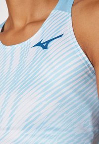 Světle modrý sportovní tank top s texturovaným vzorem, kulatým výstřihem a viditelným logem tmavě modré barvy na horním levém rohu.