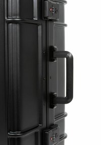 Black hard-shell suitcase with textured surface, sturdy handle, dual locking mechanism, and reinforced edges for durability.